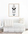 5 hand drawn butterflies in a timber frame hanging above a white cot