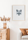 black and white art print of a portrait of a fox in a teak frame hanging on a wall in a lounge room above a lounge and sideboard