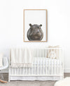 Hippopotamus Art print in a wooden frame hanging above a white cot in a nursery