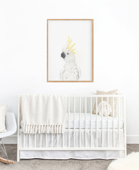 a colour pencil drawing of a white cockatoo on a white background in a teak frame hanging in a nursery above a white cot