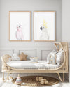 Set of 2 white cockatoo and pink galah bird prints hanging above a cane be