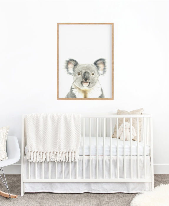 koala colour pencil illustration on a white background in a teak frame hanging above a white cot in a nursery