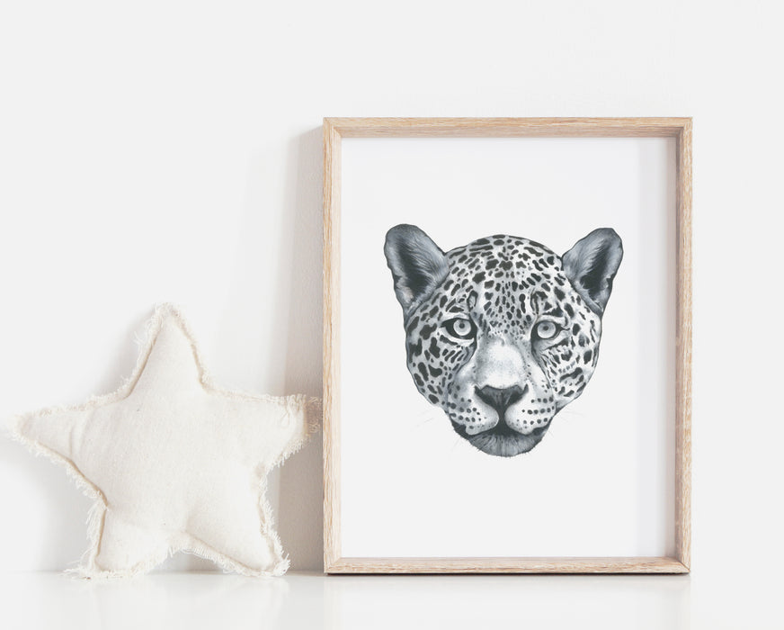 black and white drawing of a leopards portrait in a timber frame next to a white star pillow in a childrens room