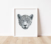 black and white leopards portrait drawing in a white frame sitting on a timber floor