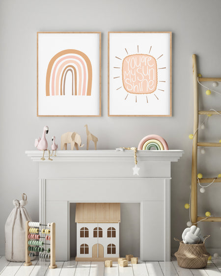Set of two rainbow and cloud nursery prints hanging above a mantlepiece in a childrens room