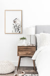  black and white colour pencil drawing of a snowy white owl in a teak frame hanging in a bedroom above a side table