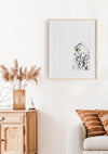 black and white colour pencil drawing of a snowy white owl in a teak frame hanging in a lounge room above a chair