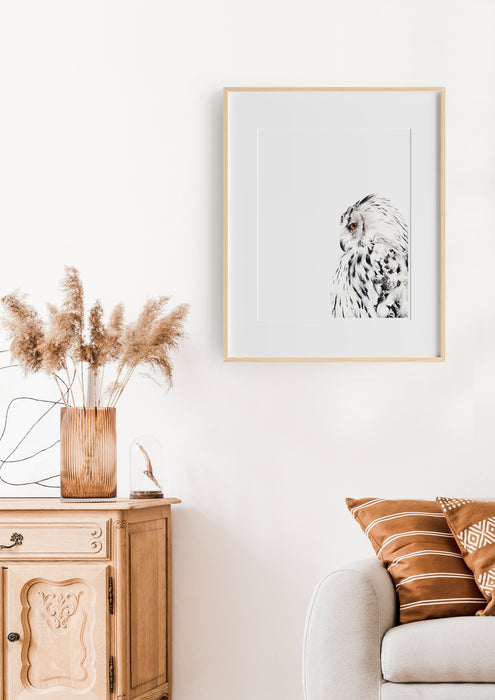 black and white colour pencil drawing of a snowy white owl in a teak frame hanging in a lounge room above a chair