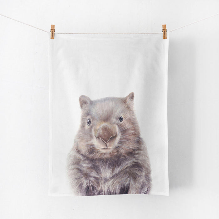 a linen tea towel with a wombat printed on it, hanging by pegs